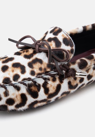 Παπούτσι loafer με καφέ και μαύρο τυπωμένο γούνινο μοτίβο λεοπάρδαλης, δερμάτινη κορδέλα δεμένη σε φιόγκο και ραφές σε στυλ μοκασίνι σε λευκό φόντο.