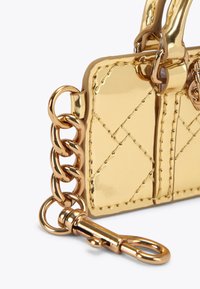 Borsa a tracolla in metallo dorato con texture trapuntata, arricchita da una tracolla a catena e chiusura. Presenta dettagli di cucitura e un emblema decorativo.