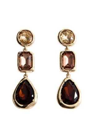Cercei lungi din metal auriu prezintă trei pietre prețioase fasetate: o piatră rotundă de culoare maro deschis în partea de sus, o piatră rectangulară de culoare bej în mijloc și o piatră în formă de lacrimă de culoare maro închis în partea de jos.