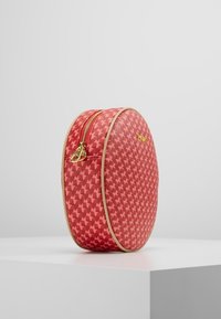 Czerwona ovalna torba w wzór houndstooth, z złotym zamkiem błyskawicznym i beżowymi wykończeniami. Wykonana z teksturowanego materiału dla zwiększenia trwałości.