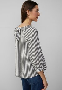 Gestreepte blouse in grijs en wit, met een strikdetail op de rug, lange mouwen en een relaxte pasvorm. Gemaakt van lichte stof.