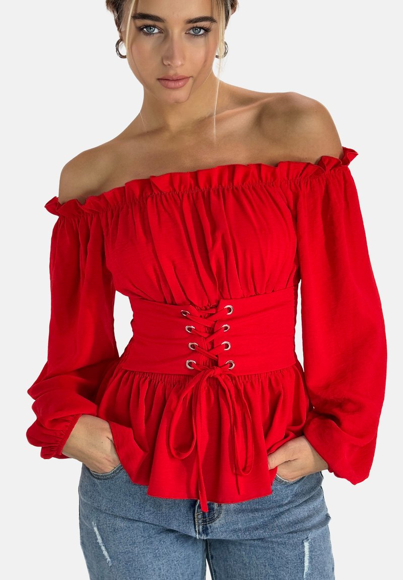 Top rosso senza spalle con dettagli a ruffle, vita elasticizzata e stringhe frontali. Tessuto morbido, maniche lunghe e orlo peplo creano una silhouette femminile.