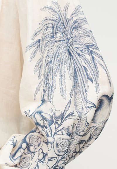 Μανίκι με λεπτομερές μπλε βοτανικό σχέδιο που απεικονίζει φοινικόφυλλα, σύκα και άλλα φρούτα σε λευκό ύφασμα, ελαφρώς σφηνοειδές στο μανσέτι.