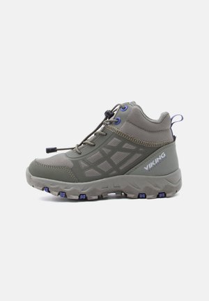 Chaussure de randonnée mi-hauteur en vert olive avec des matériaux en maille et synthétiques. Présente une semelle texturée, des lacets élastiques et des accents bleus.