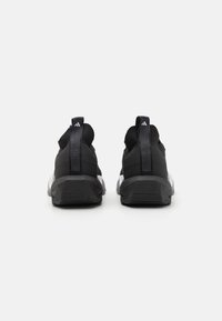 Baskets de sport noires avec un dessus texturé, une semelle blanche contrastante et des languettes de talon proéminentes. Elles présentent un ajustement serré et un design de soutien.