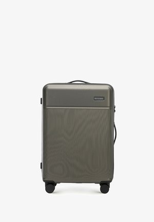 Harde koffer in donkergrijs textielmateriaal met verticale lijnen, dubbele wielen en een handvat aan de bovenkant. Bevat een logo plaat aan de voorkant.