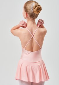 Heller rosa Ballettanzug mit überkreuzten Trägern und ausgestelltem Rock. Glatter Stoff, geeignet für den Tanz, kombiniert mit hellrosa Strumpfhosen.