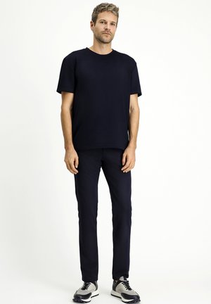 Camiseta de manga corta azul marino con cuello redondo, combinada con pantalones azules marinos a juego y zapatillas deportivas grises y negras.