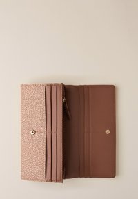 Portafoglio bifold marrone aperto, con pattina decorata, scomparti per carte, comparto per monete con zip e chiusura a scatto su uno sfondo chiaro.
