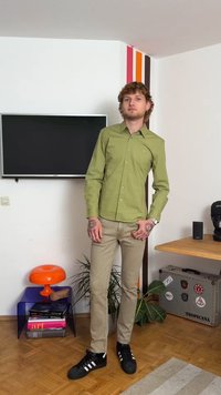 Svetlo zelena srajca s kratkimi rokavi, slim fit. Usklajena z bež hlačami in črnimi čevlji z belimi črtami. Notranji ambient z dekoracijo.