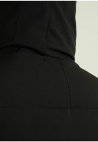 Schwarze Kapuzenjacke mit einer glatten, matten Textur, einem dezenten gestickten Logo und strukturierten Nähten auf der Rückseite.