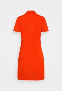 Robe polo à manches courtes de couleur orange vif, coupe droite avec col, vue de dos sur fond blanc uni.