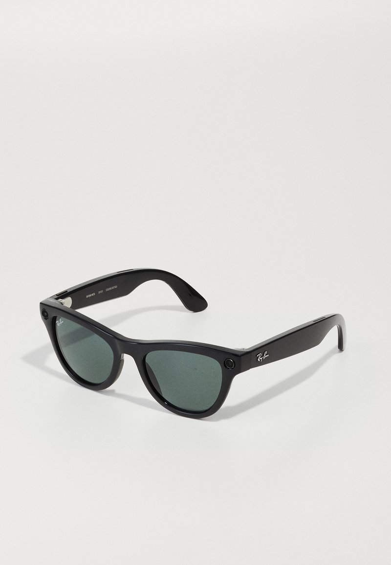 Occhiali da sole in plastica nera con lenti grigie. Presentano un design classico con montatura rotonda e logo accentato sulle astine.