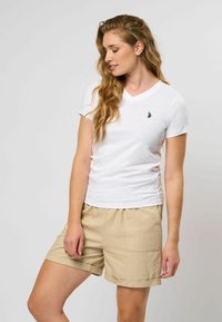 Witte korte mouwen V-hals T-shirt van katoen met een klein geborduurd logo, gecombineerd met beige shorts met zijzakken.