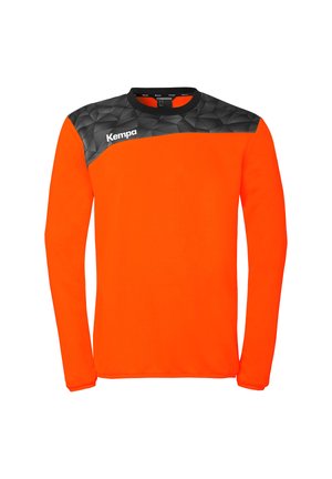 Maillot de sport à manches longues de couleur orange vif avec un motif géométrique noir sur les épaules et le logo "Kempa" sur le côté droit de la poitrine.