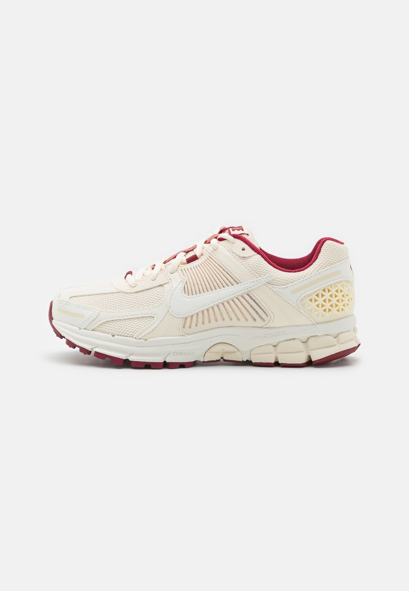 Chaussure de sport crème clair avec des accents bordeaux et un dessus en maille texturée. Dotée d'une semelle rembourrée et d'un design en nid d'abeille sur le talon.