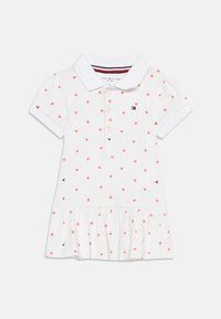 Λευκό κοντομάνικο φόρεμα πόλο με ροζ σχέδιο καρδιάς, πατιλέτα με κουμπιά, βολάν στο τελείωμα και μικρό κεντητό λογότυπο στο στήθος και τα μανίκια.