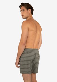 Pantaloni da bagno da uomo in verde oliva con strisce verticali nere, dotati di vita elastica e tasche laterali, progettati per comfort e mobilità.
