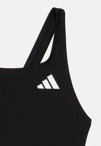 Sort sportstop med tynde stropper og en hvid Adidas-logo på øverste venstre bryst mod en ensfarvet baggrund.