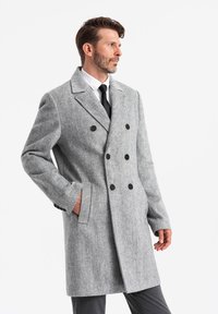 Abrigo de mezcla de lana gris, de doble botonadura, con cuello con muescas, botones y bolsillos laterales, estilizado con una silueta ajustada.