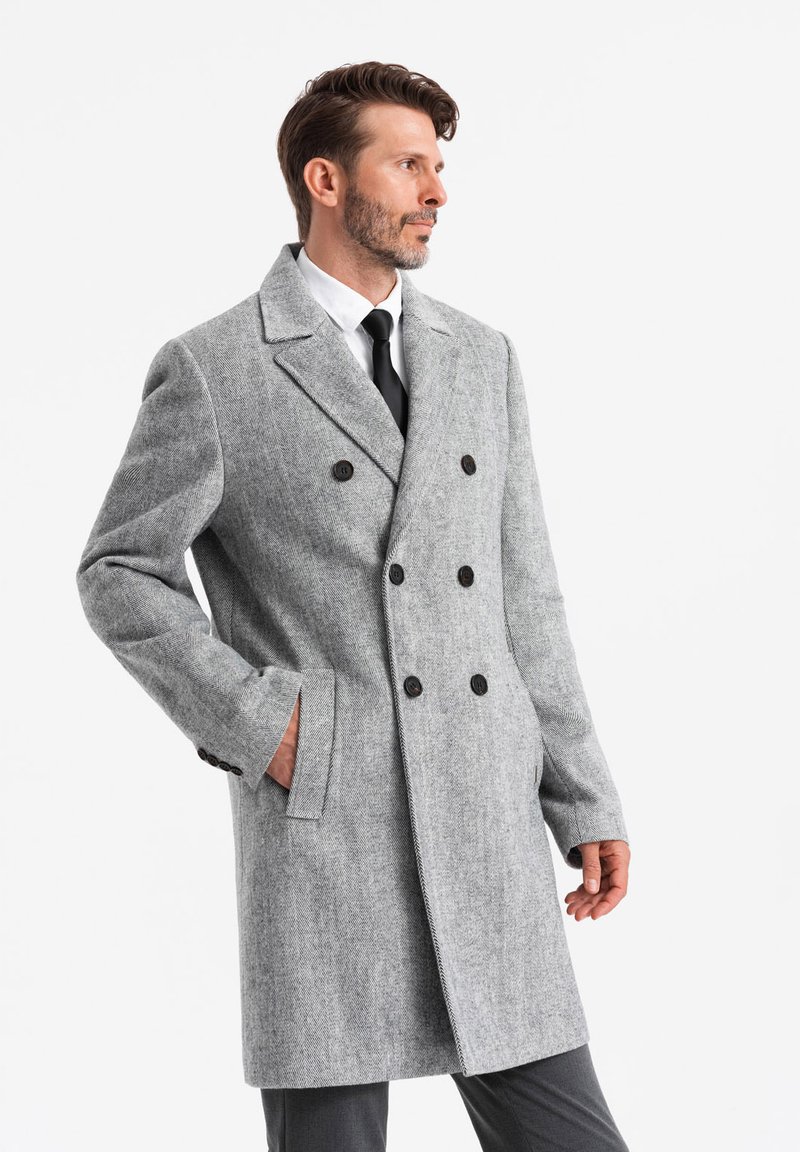 Abrigo de mezcla de lana gris, de doble botonadura, con cuello con muescas, botones y bolsillos laterales, estilizado con una silueta ajustada.
