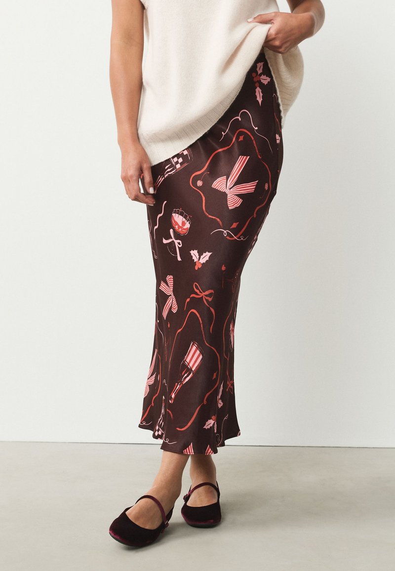 Jupe midi marron à motifs avec des accents roses comprenant des nœuds, des cannes en sucre d'orge et des motifs floraux ; texture lisse, ourlet évasé.