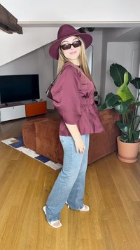 Μαρούλι μπλούζα με φουσκωτά μανίκια, ανοιχτό μπλε φαρδιά τζιν, λευκά σανδάλια με πλατφόρμα και ένα ταιριαστό μαρούλι καπέλο με φαρδύ γείσο. Καφέ φόντο.