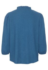 Blouse bleue texturée avec un col à volants et des manches bouffantes trois-quarts. La coupe est ample avec un ourlet droit.