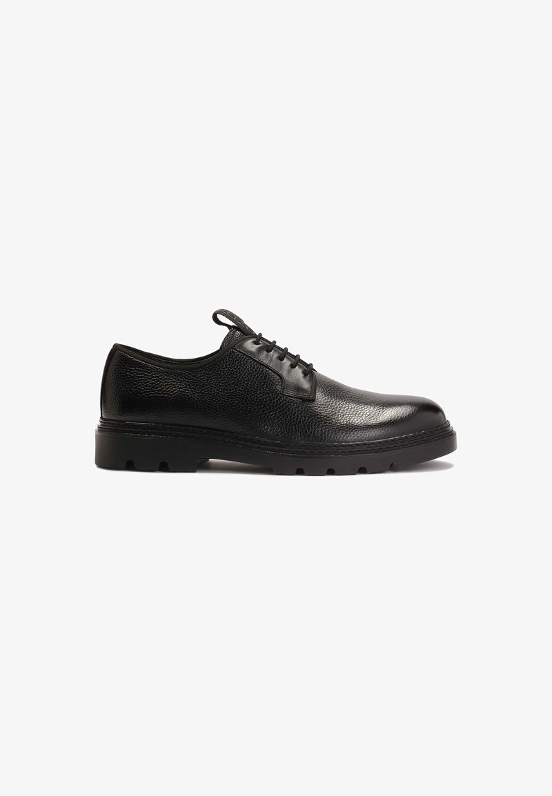 Zapatos de vestir de cuero negro con un acabado texturizado, punta redonda, diseño de cordones y suela de goma negra gruesa con patrones de relieve cortados.