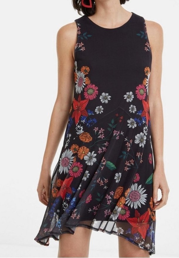 Robe noire sans manches avec imprimé floral coloré, encolure ronde et ourlet asymétrique portée par une personne avec des boucles d'oreilles rouges.