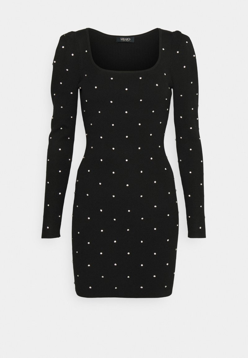 Schwarzes, geripptes Kleid mit langen Ärmeln, quadratischem Ausschnitt und verstreuten silbernen Verzierungen im gesamten Stoff. Figurnaher Schnitt.