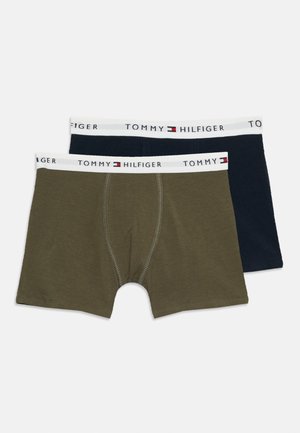 Dva páry pánskych boxeriek Tommy Hilfiger, jeden v olivovozelenej farbe a druhý v námorníckej modrej, oba s bielymi pásmi s logom značky.