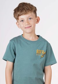 Grünes Baumwoll-T-Shirt mit kurzen Ärmeln, Rundhalsausschnitt und einem gelben Grafikdruck mit dem Text "BOFR 2014" sowie einem Blitzdesign.