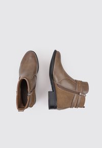 Botas de tobillo marrones hechas de cuero y ante, con una cremallera lateral, detalle de correa con remaches y un tacón bajo.
