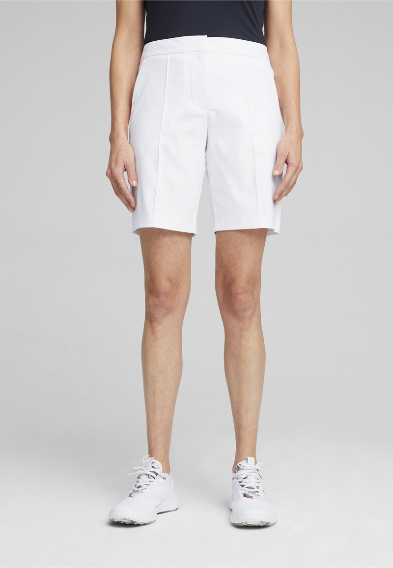 Pantalones cortos deportivos blancos con una cinturilla plana, dos bolsillos frontales y paneles cosidos. Textura suave y ajuste entallado diseñado para la actividad.