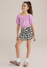 Pink textured puff-sleeve top paired with a black floral wrap skirt. Complete with pink sneakers and white socks.