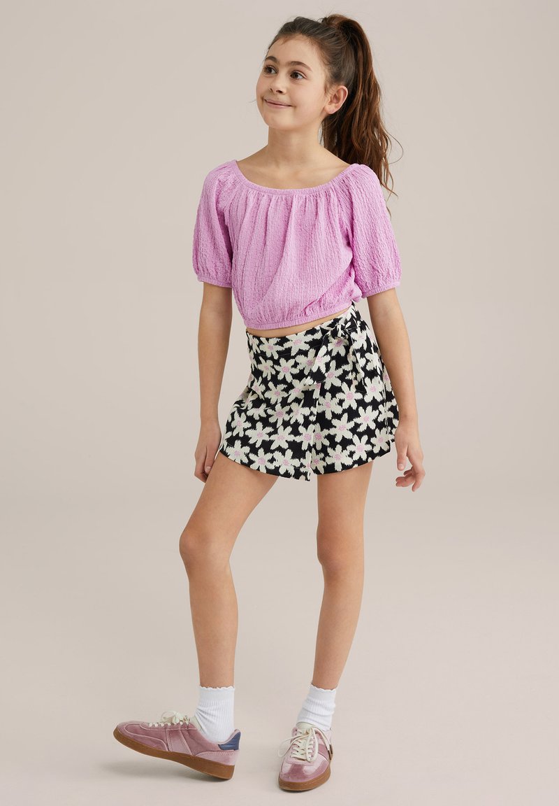 Pink textured puff-sleeve top paired with a black floral wrap skirt. Complete with pink sneakers and white socks.