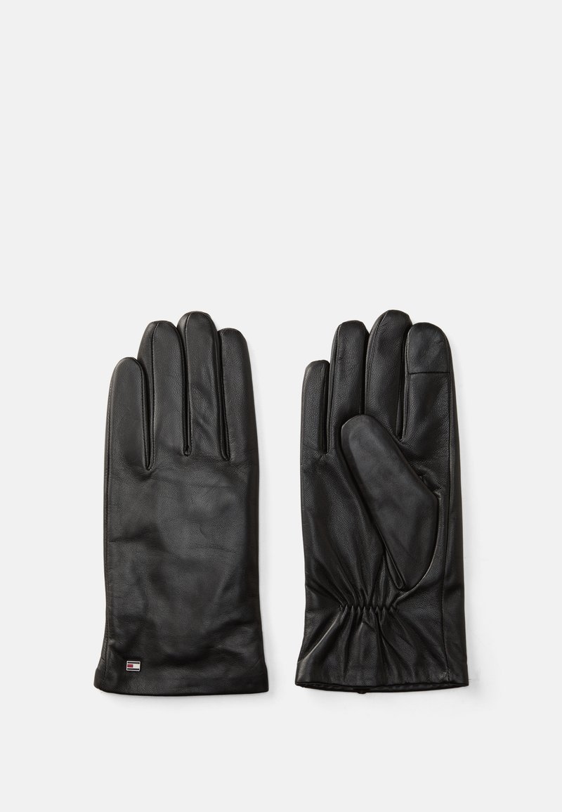 Guanti in pelle nera con una texture liscia, design a cinque dita e dettaglio arricciato sul polso. Piccolo logo del marchio sul polsino.