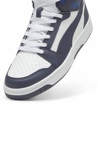 Zapatillas altas con parte superior de cuero en azul marino y blanco, puntera perforada, cordones planos blancos y suela de goma texturada.