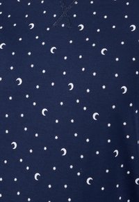 Tessuto blu navy con un motivo sparso di lune e stelle bianche, con una texture morbida e piccoli dettagli di cucitura decorativa.