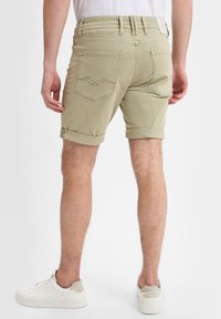 Khaki-shortsit, joissa on käännetyt lahkeet, valmistettu pehmeästä kankaasta. Ominaisuuksiin kuuluvat kaksi takataskua, joissa on hillitty design, ja vyölenkit vyötäröllä.