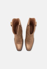 Bronze metallic ankle boots with pointed toes, textured upper, and pull-tab on sides. Interior is lined in brown fabric.