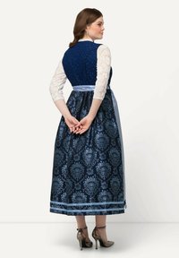 Vestido tradicional con un cuerpo de jacquard azul, falda con estampado floral, acentos de cinta azul clara y mangas de encaje. Tacones altos plateados.