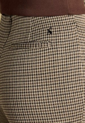 Byxor i brunt och beige hundtandsmönster med texturerat tyg. Har en bakficka och svart broderad detalj ovanför fickan.