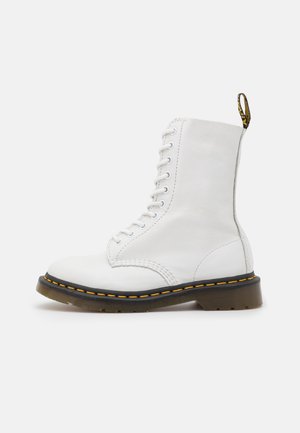 White leather lace-up ankle boot with black sole, yellow stitching, and branded pull tab on plain background.