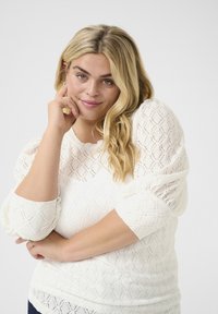 Pull blanc avec un motif en diamant, tissu texturé et manches bouffantes trois-quarts. Matière douce et légère.