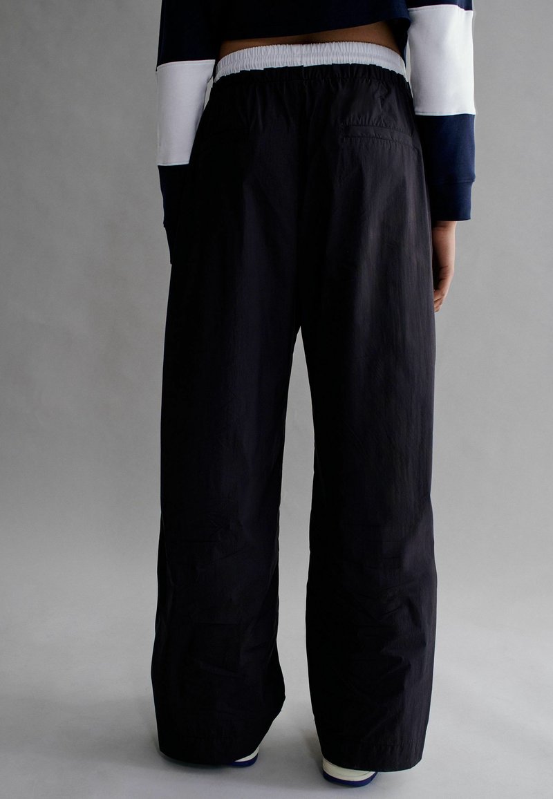 Pantalons larges noirs avec une taille élastique et un tissu léger et doux, au design simple et fonctionnel.