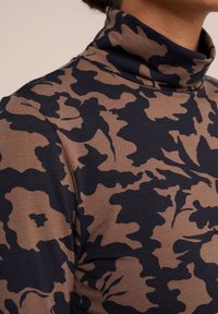 Hnědý a námořnický rolák s květinovým vzorem. Měkká tkanina, přiléhavý střih a vysoký límec. Má texturovaný vzhled a hladký povrch.