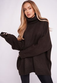 Übergrößiger, dunkelbrauner Rollkragenpullover mit gerippter Textur, weiten Ärmeln und lockerer Passform, mit geradem Saum und seitlichen Taschen.