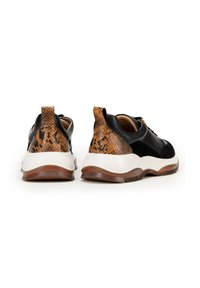 Czarno-skórzane i zamszowe sneakersy z teksturowanym, brązowym, wężowym wzorem na pięcie i białą podeszwą. Posiadają pętelkę do zakupu i kontrastujące sznurówki.